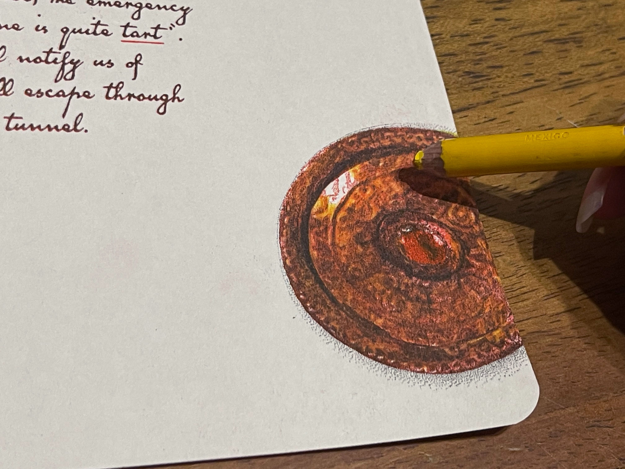 Photo of a printed brooch being hand coloured with a yellow pencil.